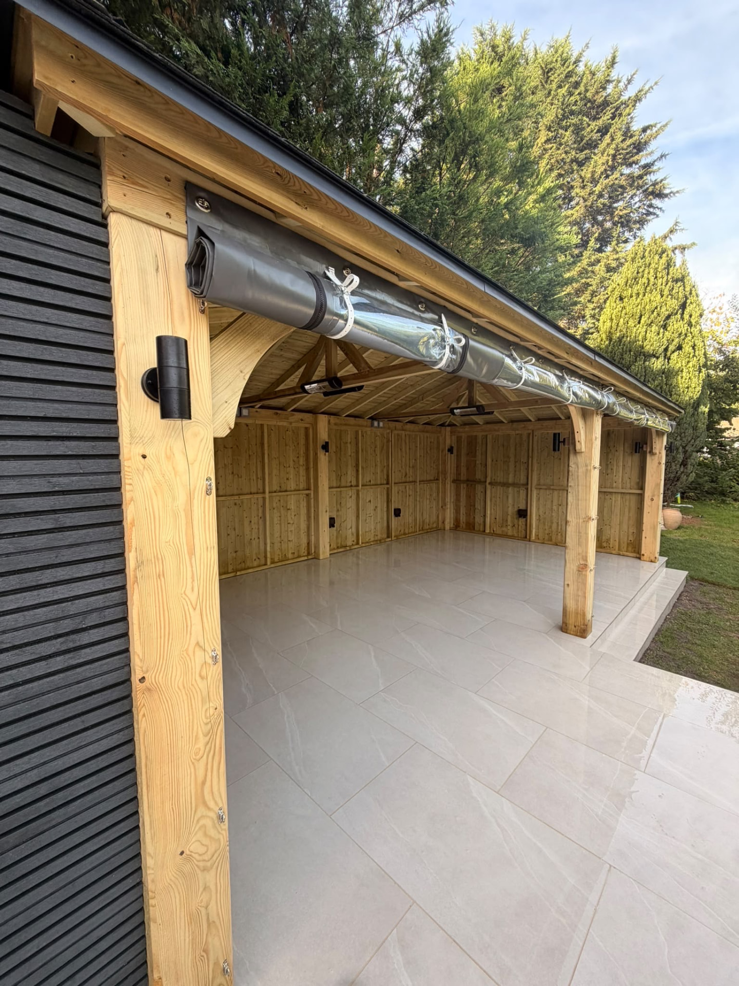 Covered timber garden room with roll-down screens and wall lights