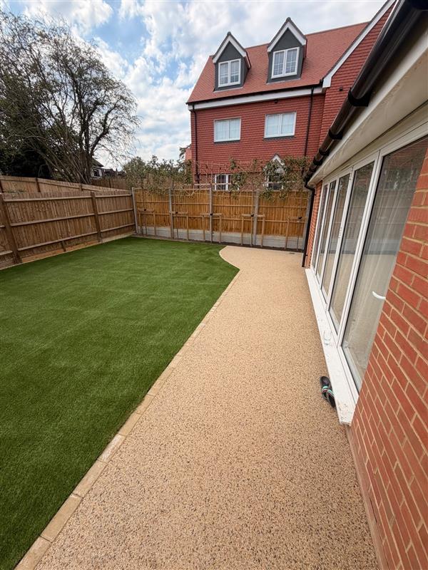 Artificial lawn with resin bound path and close board fencing in a rear garden