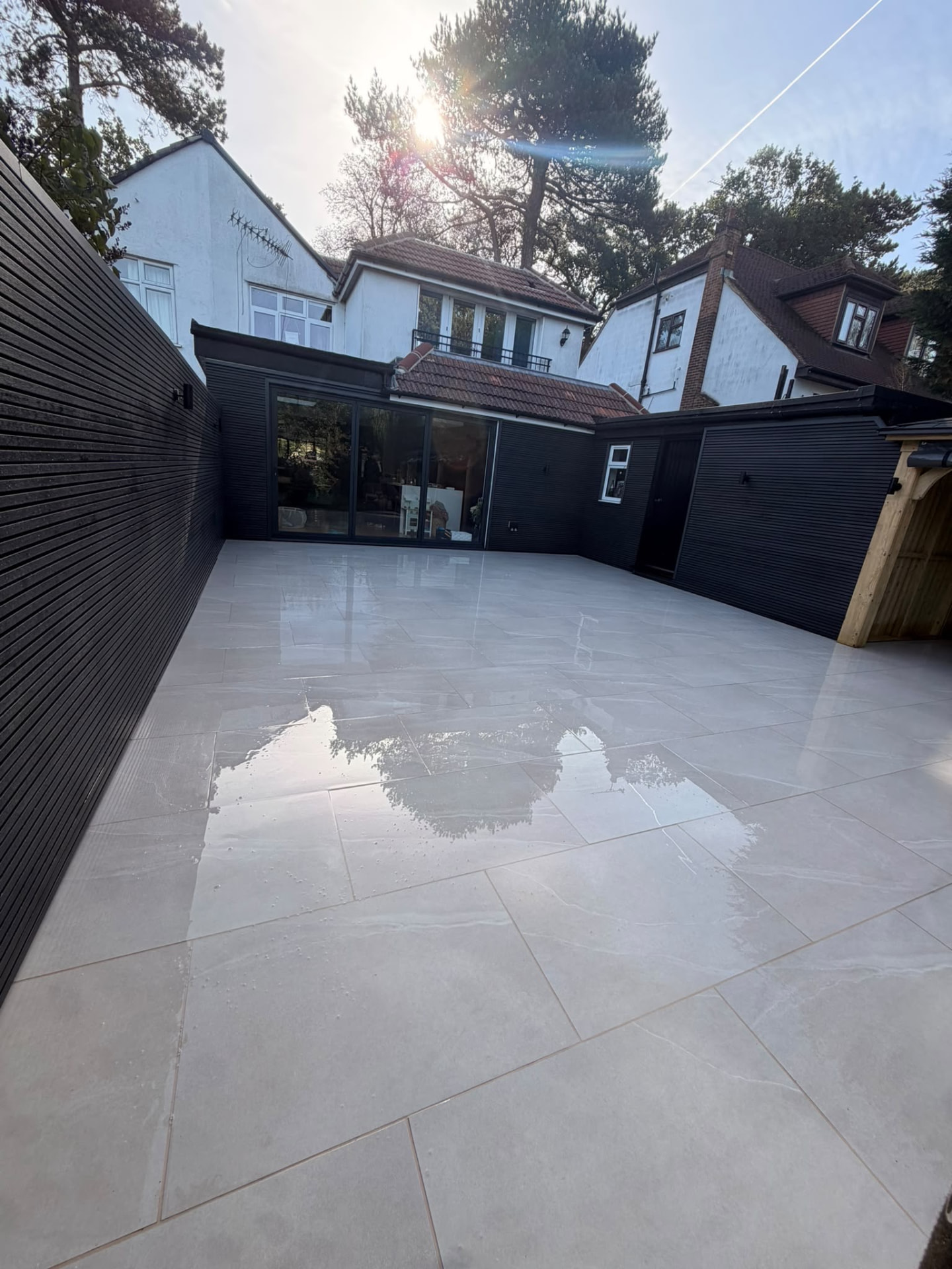 Porcelain patio in front of a black-clad extension with sliding doors, built by Hodges Building & Landscaping